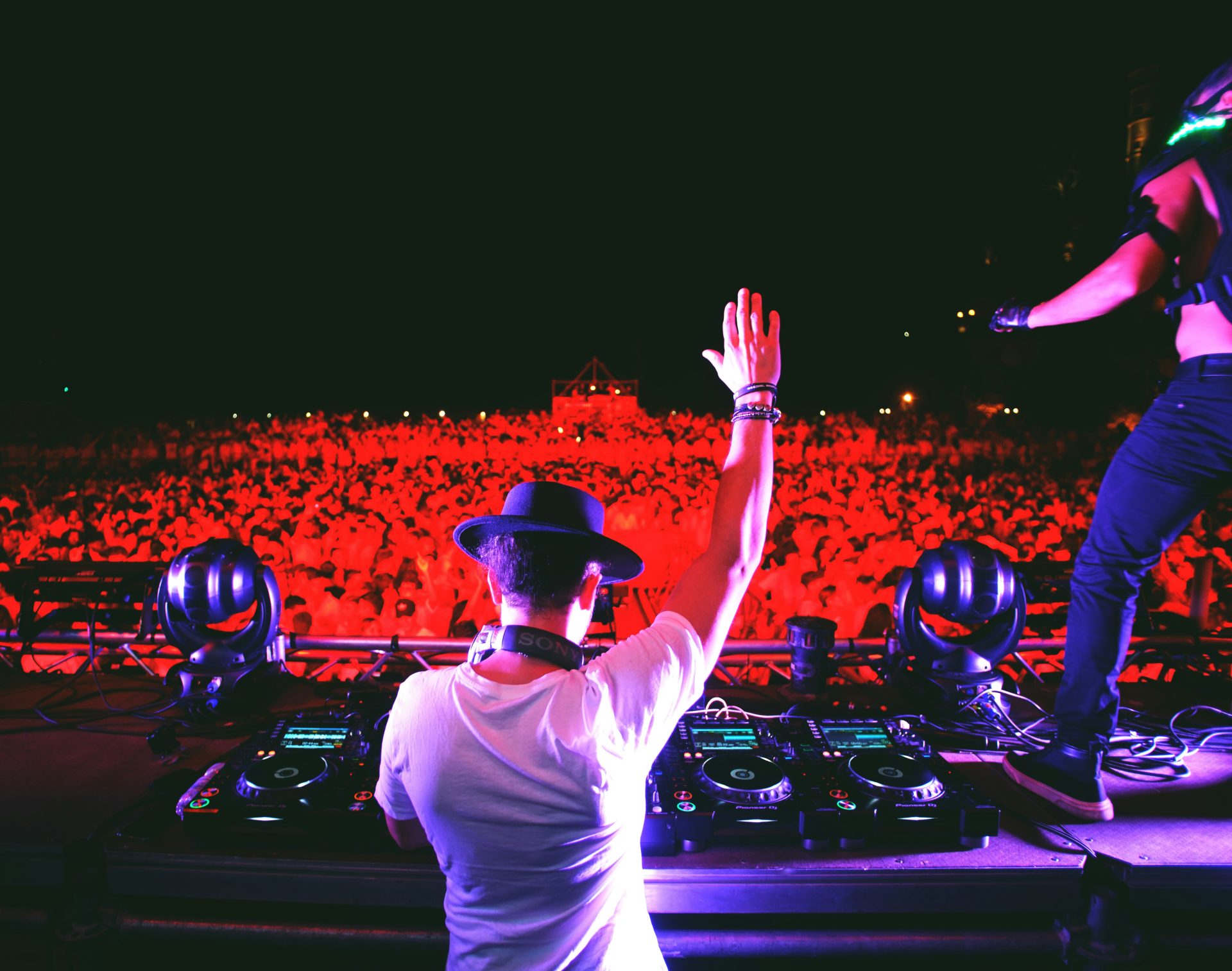 homme en t-shirt blanc et casquette noire debout devant le contrôleur dj